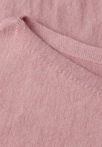 Hellrosa Strickpulloverstoff mit einer weichen текстur, der einen glatten Ausschnitt und ein dezentes Rippmuster an den Kanten hat.