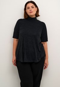 Top negru cu maneci scurte și guler înalt, cu un model texturat și o croială relaxată, asortat cu pantaloni negri largi.
