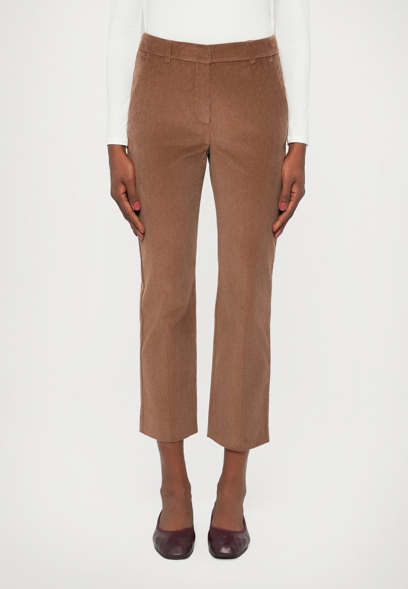 Pantaloni din corduroy maroniu, cu croială dreaptă, lungime scurtă, dungi verticale subtile și talie standard. Purtați cu pantofi de culoare bordo închis.