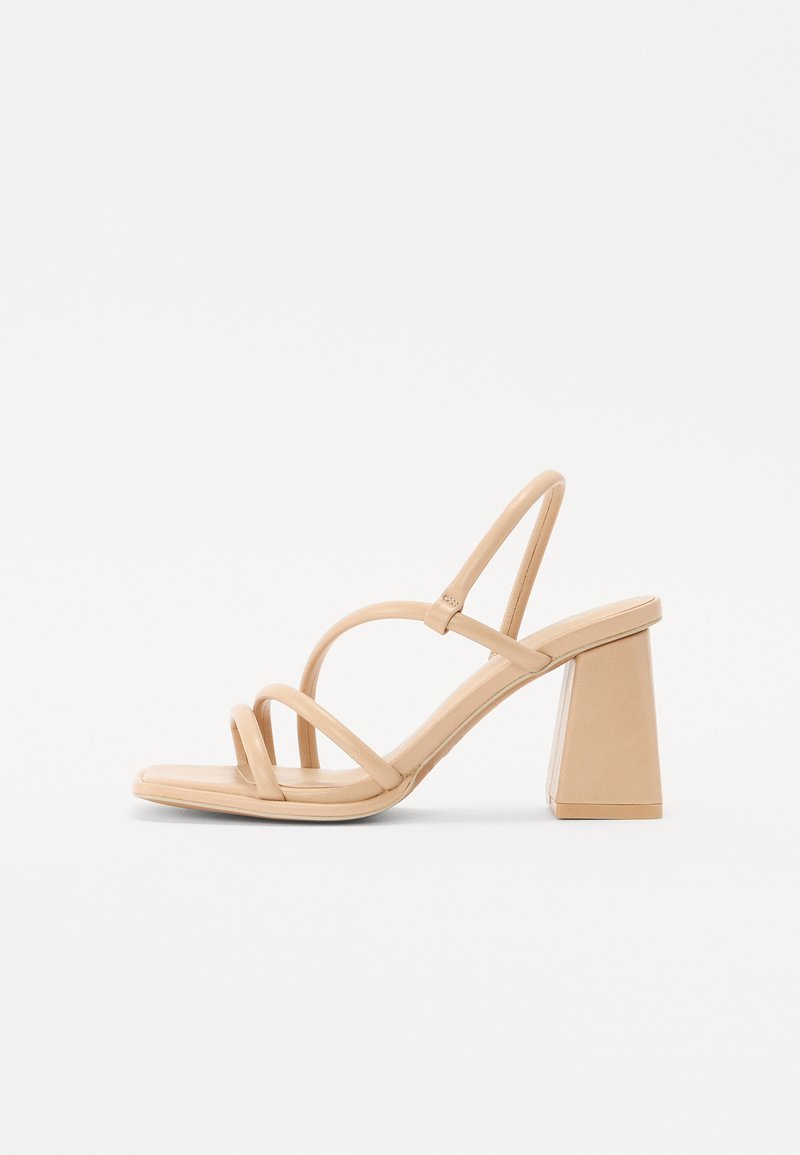 Nude høyhælte sandaler med firkantet blokkhelle, tynne stropper og en glatt, blank overflate. Enkel design med stropper på overdelen.