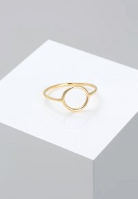 Goldener Ring mit einem dünnen Band und einem offenen Kreisdesign in der Mitte, das eine glatte, polierte Oberfläche auf einem weißen Hintergrund aufweist.