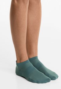 Textured teal ankle socks with a ribbed cuff and varied knit patterns, designed for comfort and fit around the foot.