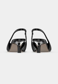 Μαύρες γόβες από γυαλιστερό δέρμα με λουρί στην πλάτη, τετράγωνη μύτη και χαμηλό χοντρό τακούνι. Ο σχεδιασμός περιλαμβάνει ομαλές καμπύλες και ανοιχτή πίσω πλευρά.