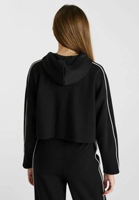 Korte zwarte hoodie van een zachte, textuurstof, met een capuchon met koord en contrasterende witte zijstrepen langs de mouwen.