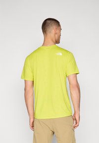 Camiseta de manga corta en un brillante color verde lima con un sutil patrón texturizado y un logo blanco en la parte posterior, fabricada en un material ligero.