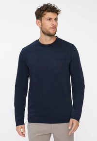 Navyblaue Langarm-T-Shirt aus Baumwolle mit Rundhalsausschnitt und einer Brusttasche. Glatte Textur und taillierte Passform.