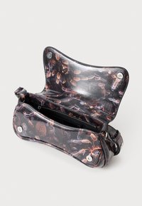 Pieni musta olkalaukku, jossa on kiiltävä pinta, ja jossa on abstrakteja oransseja ja violetteja höyhenkuvioita. Laukussa on auki oleva läppä magneettisulkimella ja sisällä vetoketjullinen tasku.