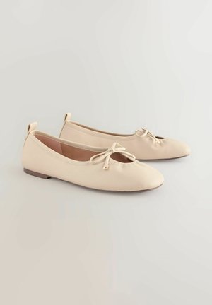 Beige Ballerinas mit einer abgerundeten Spitze, einer kleinen Schleifendetail und einer niedrigen, flachen Sohle. Glatte Textur mit minimalistischem Design.