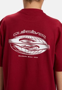 Bordeaux katoenen T-shirt met een grote witte graphic van een wereldbol met de tekst "Quiksilver" en een S-vormig logo, en "Worldwide Since 1969."