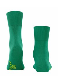 Ein Paar grüne Socken bis zur Mitte der Wade mit gerippten Bündchen, die Fersen und Sohlen zeigen; gelber Text "FALKE RUN 39-41" auf einer Sohle.