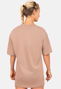 Overmaat beige t-shirt met korte mouwen, geribbelde textuur en een ronde halslijn. Heeft een effen achterkant en een ontspannen pasvorm.