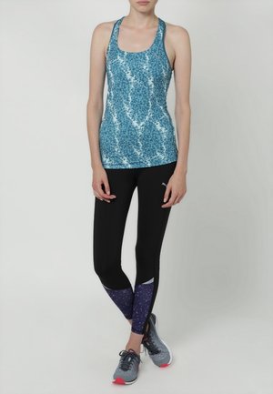Blauw patroon tanktop met een racerback ontwerp, gecombineerd met zwarte leggings met paarse bloemenaccenten. Grijze sneakers maken de look af.