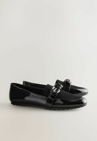Sorte loafers lavet af glat patenteret læder og blød ruskind. Har et blankt bånd med en dekorativ knude og flad gummisål.