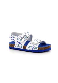 Sandalias blancas con acentos azules, que presentan dos correas ajustables y una suela de corcho. Los diseños incluyen notas musicales y patrones verdes.