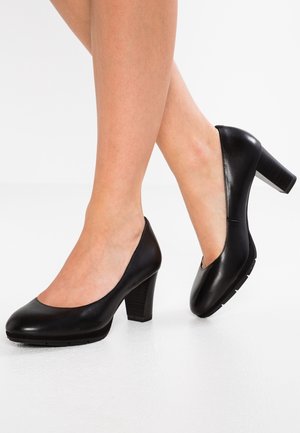 Czarne skórzane buty na wysokim obcasie z okrągłymi czubkami, z obcasem o fakturze przypominającej drewno i gładką powierzchnią, na białym tle.