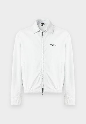 Balta korduroja jaka ar pilnu priekšējo rāvējslēdzēju, apkakli, sānu kabatām un "Armani Exchange Milano" logo uz krūtīm.