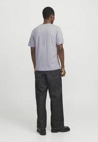 Lys lilla korte ærmer t-shirt, glat stof, afslappet pasform, parret med mørke denim jeans med baglommer og kontraststing.