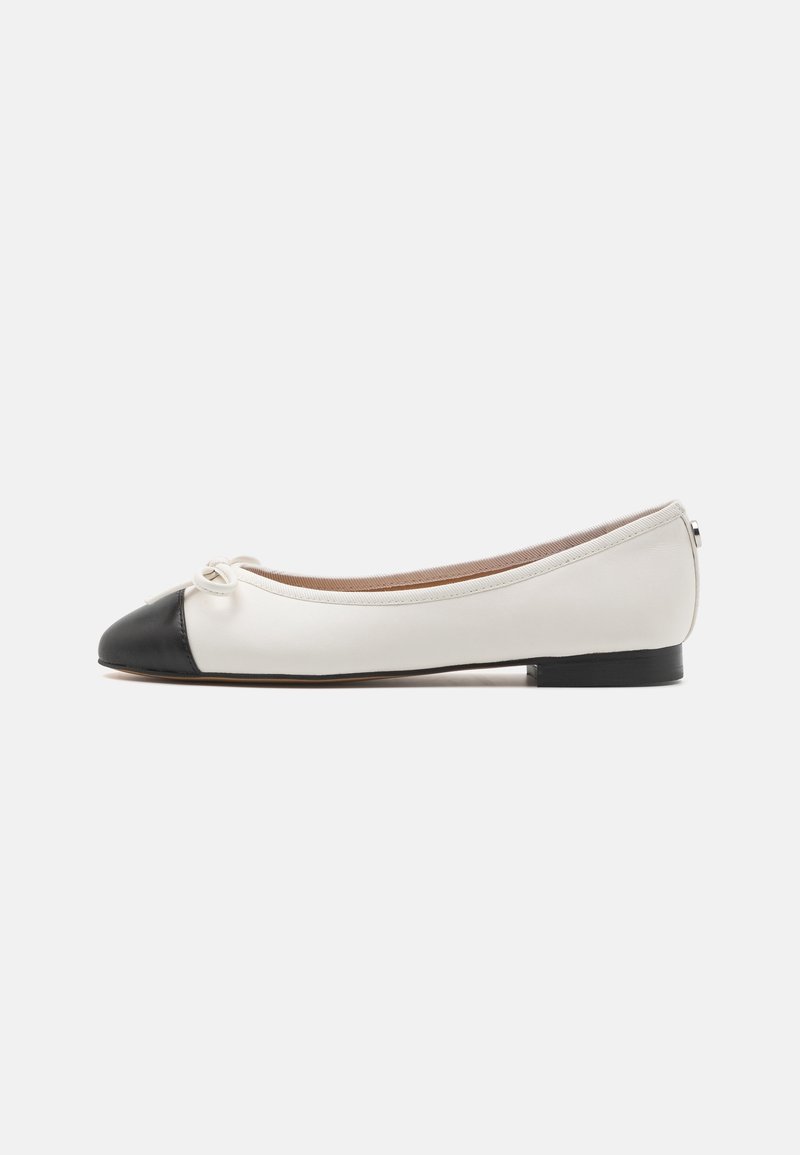 Chaussure ballerine blanche avec bout noir et petit détail de nœud sur fond blanc uni.