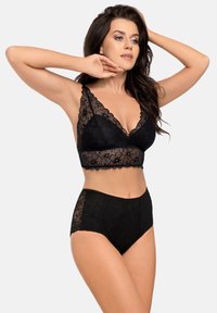 Svart spetsbralette med v-ringad design och scallopade kanter, tillsammans med höga svarta spetsunderkläder med blommönster.