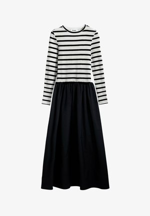 Vestido de manga larga a rayas con textura acanalada en blanco y negro, con una parte superior ajustada y una falda fluida negra. Escote redondeado.