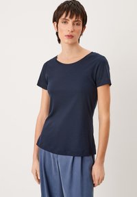 Marineblauwe T-shirt met korte mouwen in een zachte, gestructureerde stof, met een ronde halslijn en een relaxte pasvorm, gecombineerd met lichtblauwe geplooide broek.