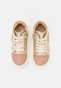 Sneakers z beżową metaliczną cholewką, jasnoróżowym noskiem i sznurówkami, z wielokolorowymi akcentami po bokach oraz teksturowanym wykończeniem.