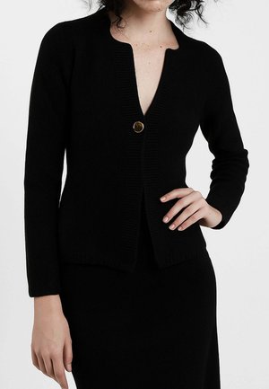 Cardigan nero lavorato a maglia con scollatura a V, dotato di una chiusura con un singolo bottone dorato e texture a coste lungo i polsini e l'orlo.