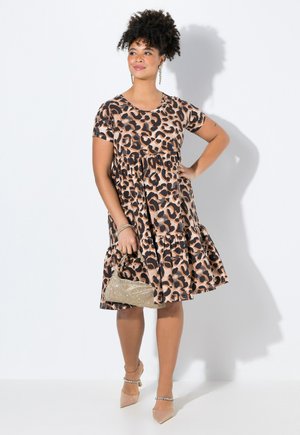 Leopardenmuster Kleid in Beige, mit kurzen Ärmeln, gestuftem Design, runder Halslinie, kombiniert mit einer metallischen Handtasche und nudefarbenen High Heels. Weicher Stoff.