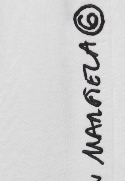 Tecido branco com texto bordado em preto, apresentando um estilo de escrita à mão contínua com acentos circulares.