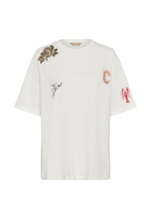 Camiseta blanca de manga corta con parche de rosa marrón en el hombro, pájaro negro volando en el pecho, parche "C" en rosa y marrón, y langosta roja en la manga.