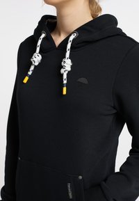 Sweat à capuche noir avec cordon de serrage blanc et jaune, logo parapluie brodé, et une poche avant. Texture de tissu lisse.