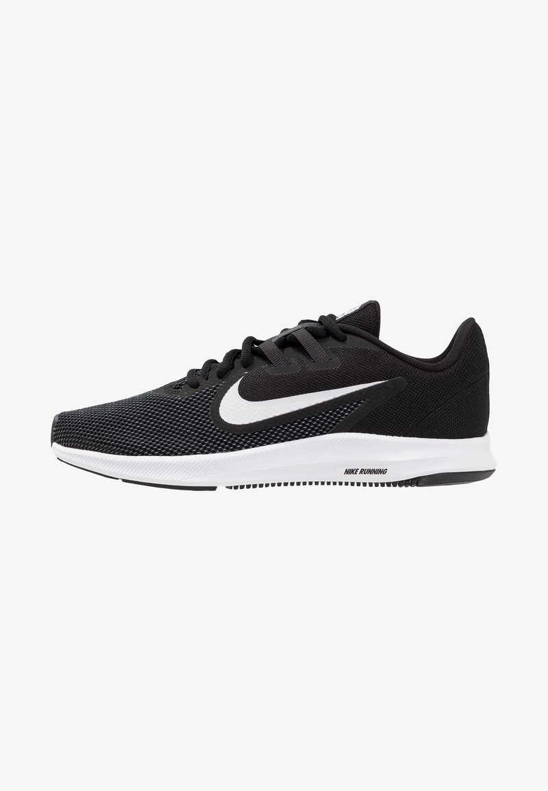 Chaussure de sport noire avec tige en mesh, swoosh blanc de Nike, système de laçage et semelle texturée. Comprend un amorti et un design à coupe basse.