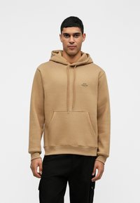 Μαύρη φούτερ με κουκούλα από μείγμα βαμβακιού. Διαθέτει μπροστινή τσέπη καγκουρό, ριγωτές μανσέτες και μικρή εκτύπωση λογότυπου στο στήθος.