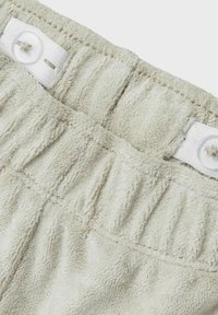 Lys beige bomulds-shorts med en struktureret, blød overflade. Har en samlede talje og en enkelt hvid knaplukning.