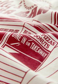 Tela crema con gráficos y texto en rojo brillante relacionados con ofertas de comida. El diseño incluye rayas y varios nombres de alimentos.