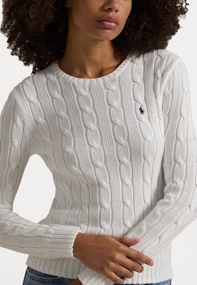 Maglione bianco a colletto rotondo a coste, con polsini a costine e un piccolo logo blu sul petto. Materiale morbido e texturizzato.