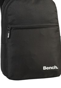 Zwarte rugzak met een hexagonaal patroon op de lagere voorkant, voorzien van een ritsvak en het witte "Bench" logo aan de zijkant. Gemaakt van duurzaam materiaal.