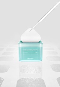 Pince tenant un tampon de coton au-dessus d'un pot bleu étiqueté Madecassoside Blemish Pad par Mediheal avec des tampons texturés sur une surface blanche.