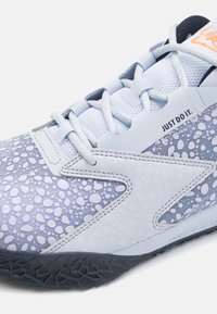 Scarpa da atletica azzurro chiaro con design maculato, parte superiore in rete, materiale testurizzato e suola in gomma grigia con un motivo di battistrada unico.