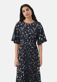 Abito in tessuto blu navy scuro con motivi a foglia di metallo argento. Presenta maniche a sirena corte e una gonna plissettata, con vita elastica.
