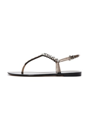 Zwarte platte sandalen met een doorschijnende band en een bedelversiering. Beschikt over een eenvoudig T-bar ontwerp en een verstelbare enkelgesp.