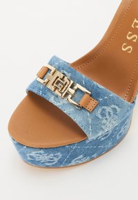 Denim plattform sandaler med blått stoffoverdel, brune lærdetaljer og gullspenner på stroppen. Design med lukket tå.