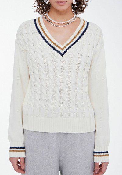 White knitted sweater with a V-neck, cable knit pattern, and striped accents in navy, gold, and white at the neckline and cuffs.