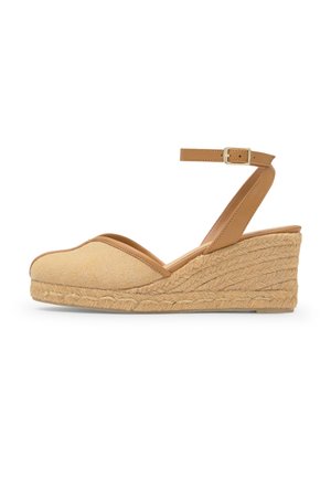 Sandalia de cuña beige con puntera cerrada, plataforma de cuerda tejida y correa de tobillo marrón claro con hebilla dorada.