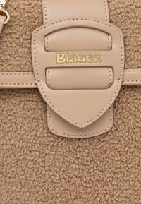 Borsa in tessuto peloso beige con superficie testurizzata, dotata di una tracolla liscia in pelle marrone chiaro e dettaglio con logo "Blauer" in oro sulla chiusura.
