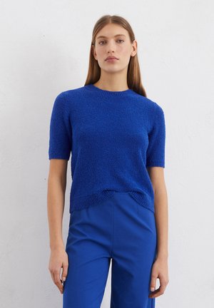 Blue short-sleeve sweater with a textured fabric, rounded neckline, and a slightly curved hem. Paired with matching blue trousers.