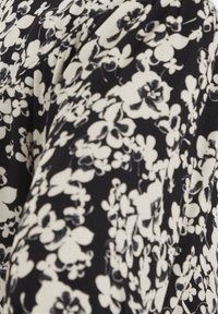 Černá látka s květinovým vzorem v bílé barvě. Design zahrnuje různé květiny a botanické prvky s jemnými detaily.