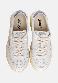Sneakers bianchi in pelle con accenti beige, design a punta rotonda, dettagli perforati e marcatura prominente "AUTRY MEDALIST" sulla linguetta.