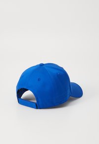 Blå baseballcaps med buet visir, myk stoff, justerbar stropp bak og en knapp på toppen. Ensfarget uten mønstre.