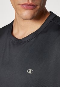 Sort kortærmet t-shirt i et glat, let stof. Har en rund halsudskæring og et lille sølvlogo på brystet.